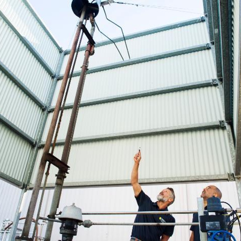 Two men inside a facility and looking up at equipment
