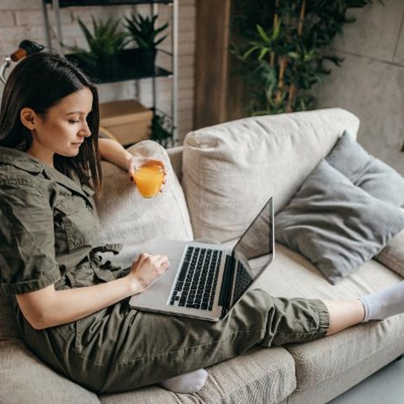 A woman sitting on a lounge with a laptop and coffee