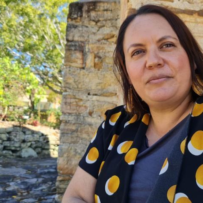 Woman sitting outside beside sandstone wall