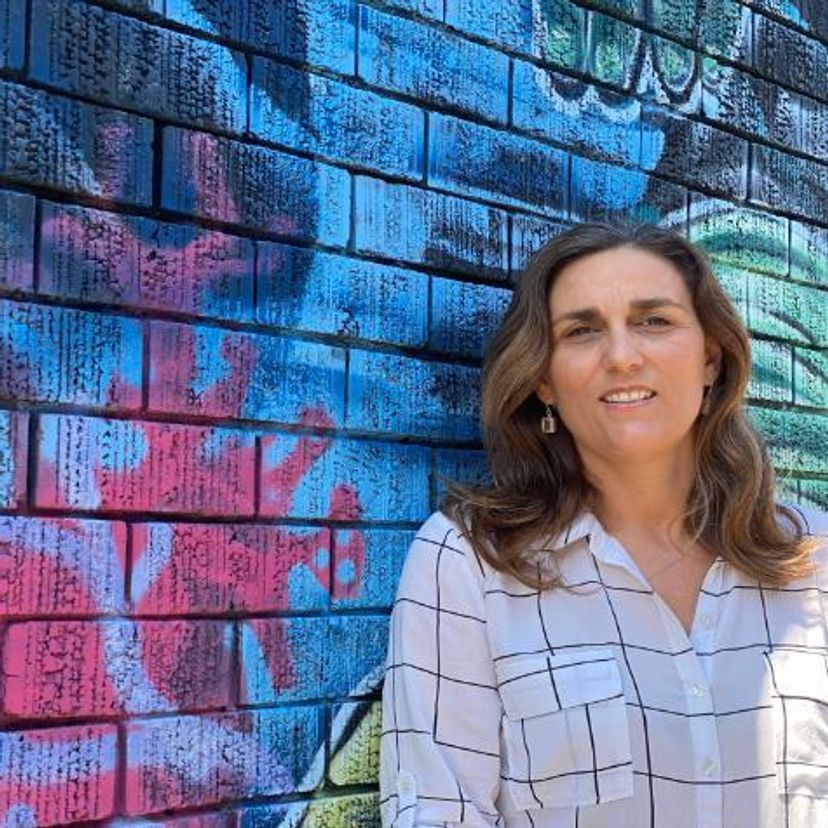 Woman leans against a colourful wall