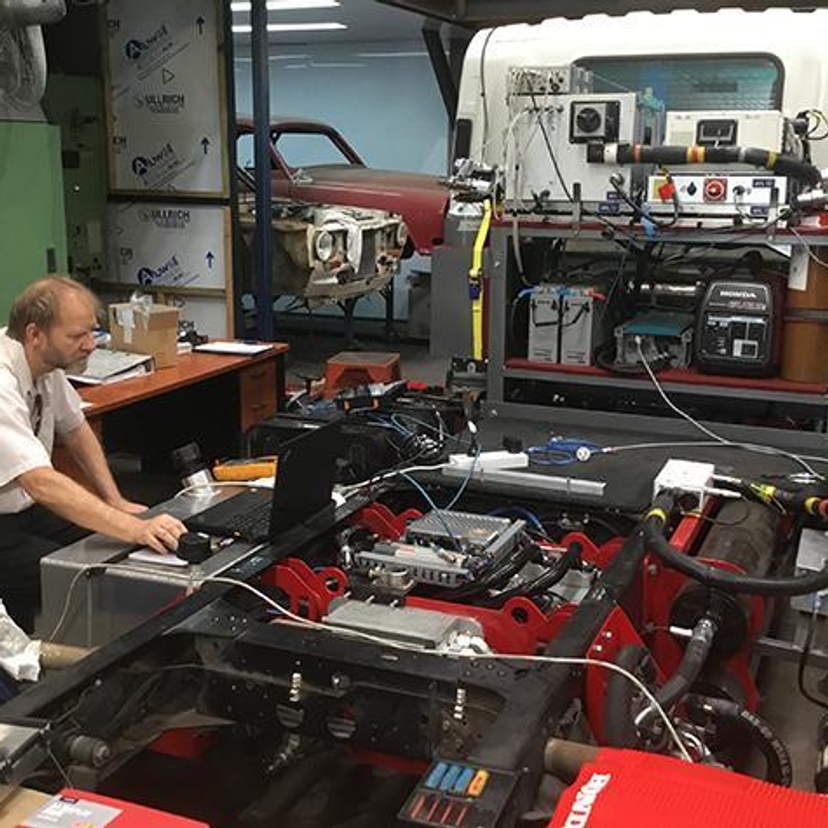 Man in front of a laptop working on the engine of a truck