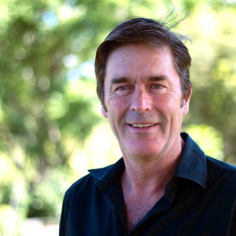A man smiling and wearing a dark shirt