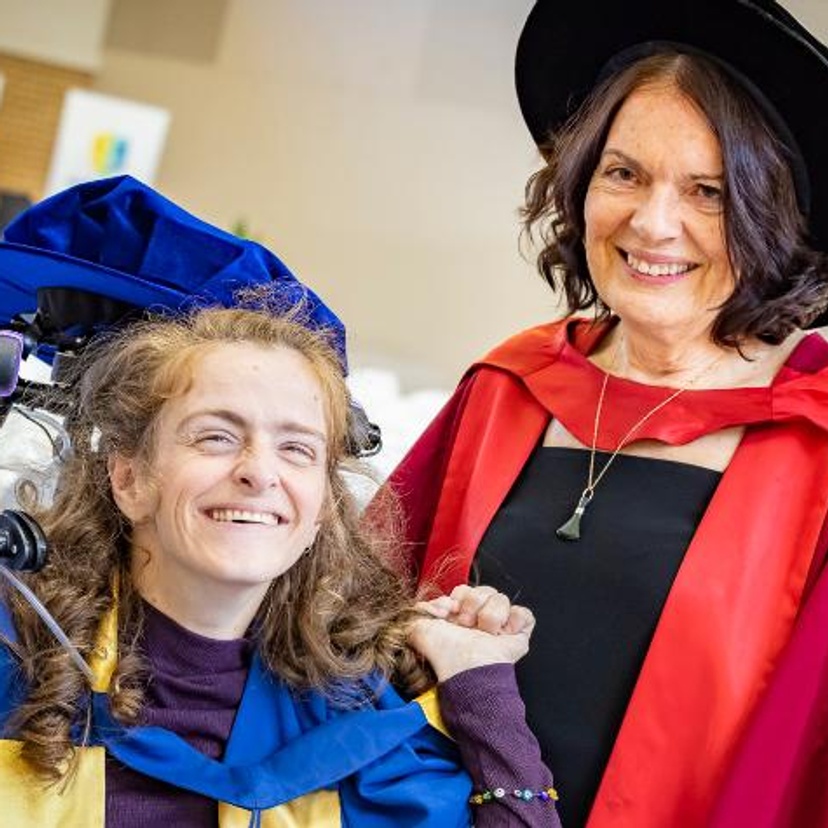 A woman in blue academic gown with a woman in red academic gown.