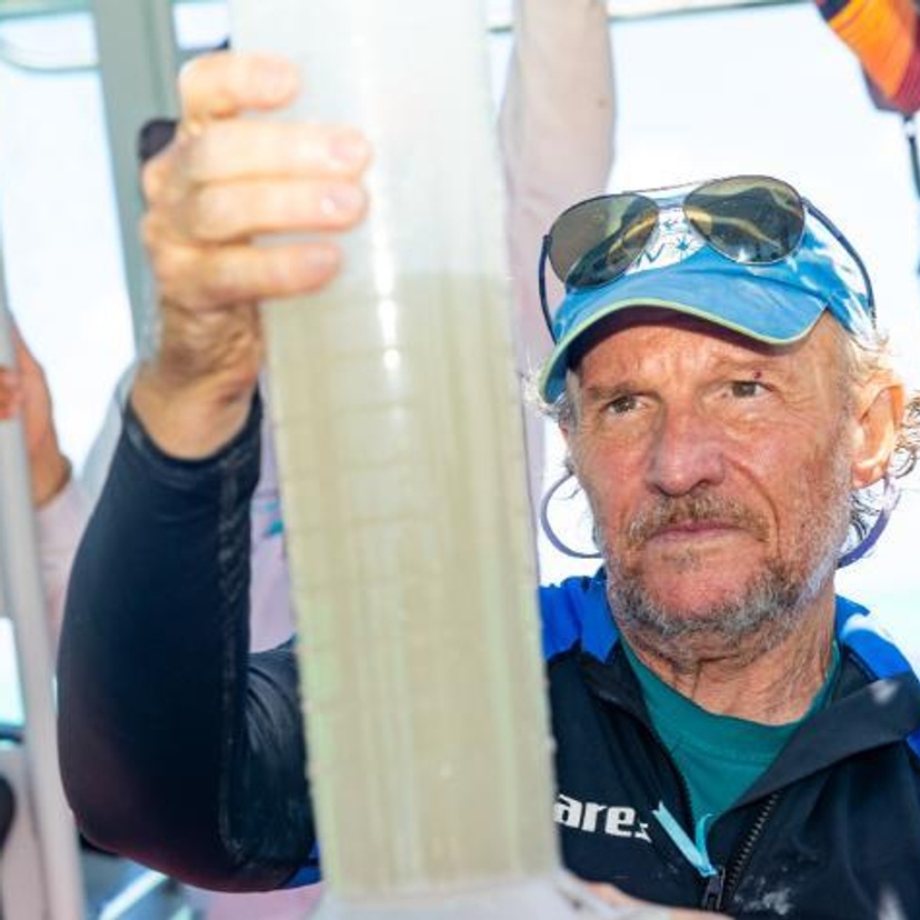 A man inspects a large water container he is holding.