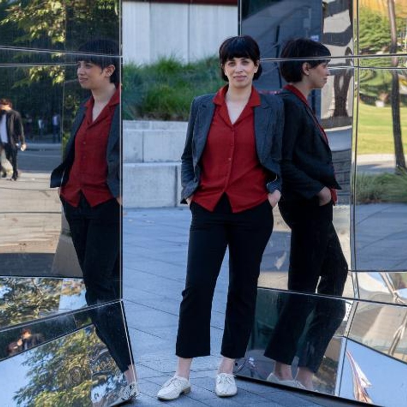 A woman stands in front of curved mirrors