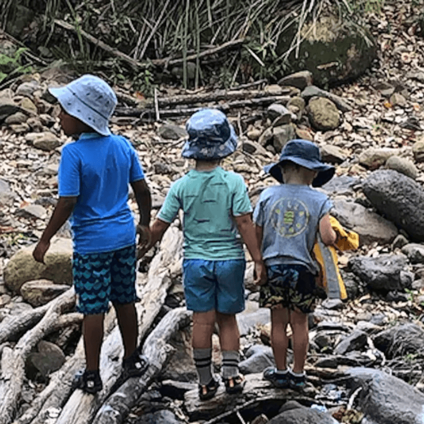 Three children playing at a stream
