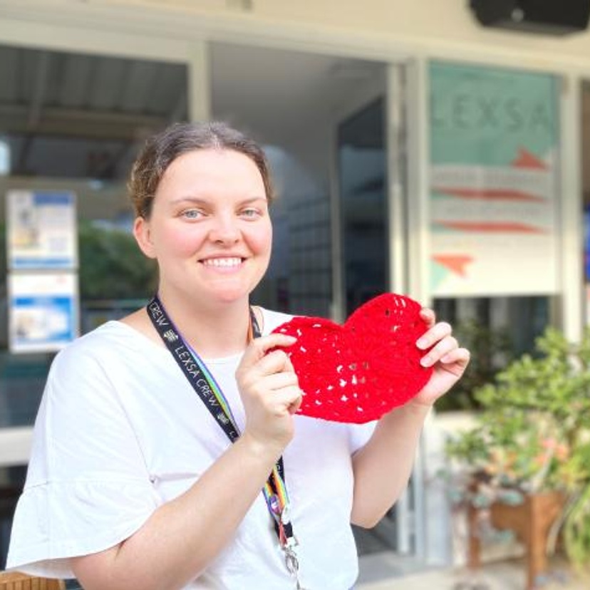 A woman holding a heart in front of the Lismore Lexsa office