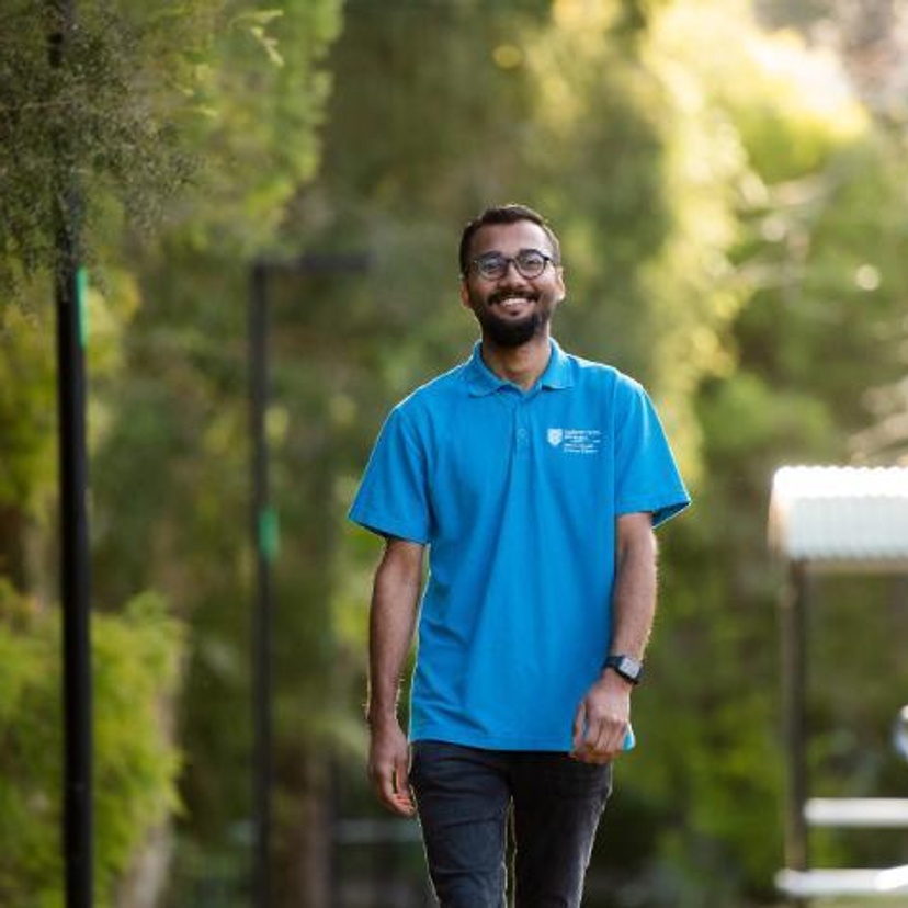 A student in a blue shirt walking on Lismore campus