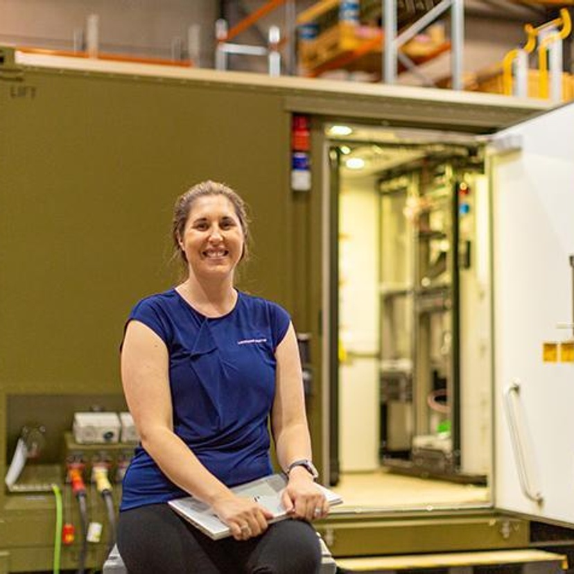 A woman in front of a metal container