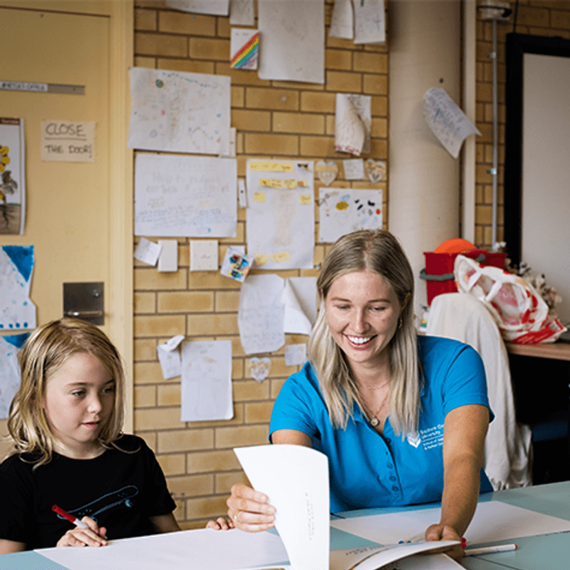 Student from The Living School with occupational therapy student in classroom looking at book