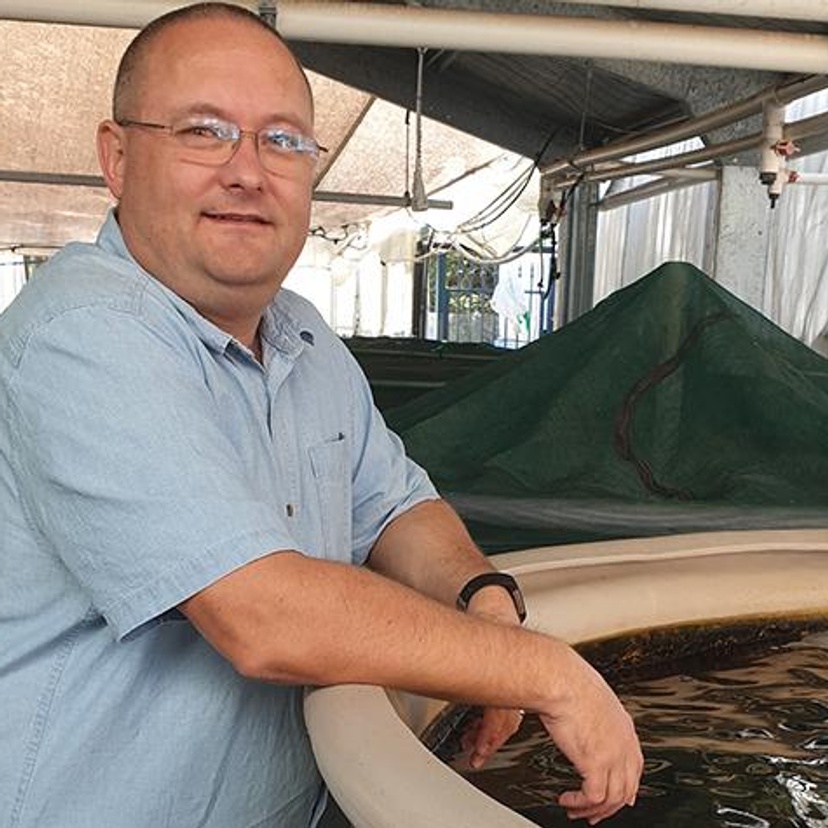 A man leaning against marine tanks.