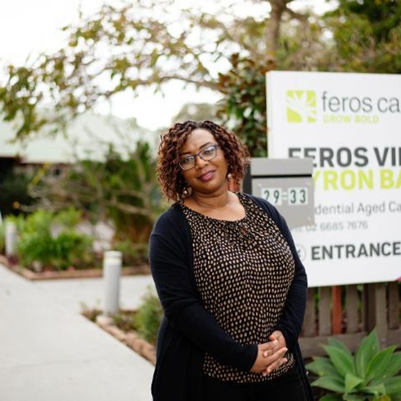 Nurse standing in front of Feros Village sign
