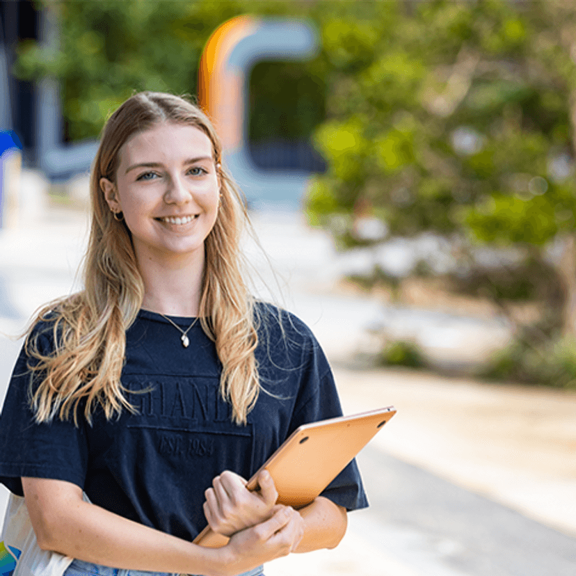 Student standing at Gold Coast campus holding laptop