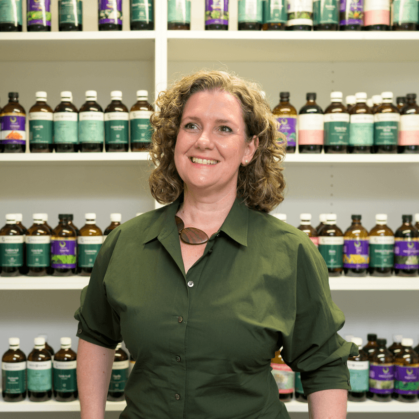 Naturopath Carla O'Brien stands in front of a wall of natural medicines