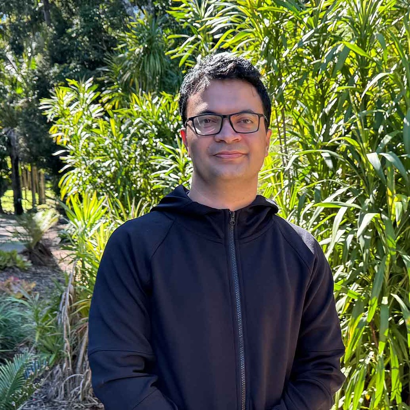 Suman Regmi standing in front of greenery wearing black jumper