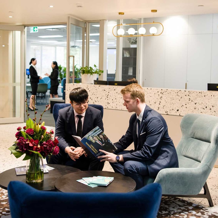 Two male Tourism and Hotel Management students sit in the foyer of The Hotel School - Melbourne.