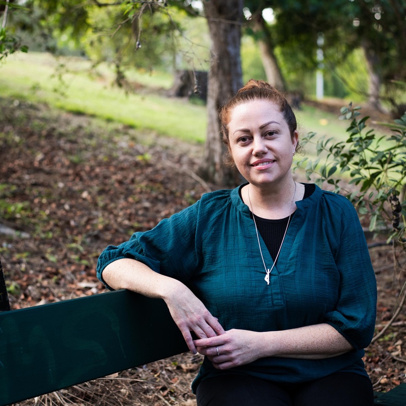 A woman sitting on a bench in a parkland setting
