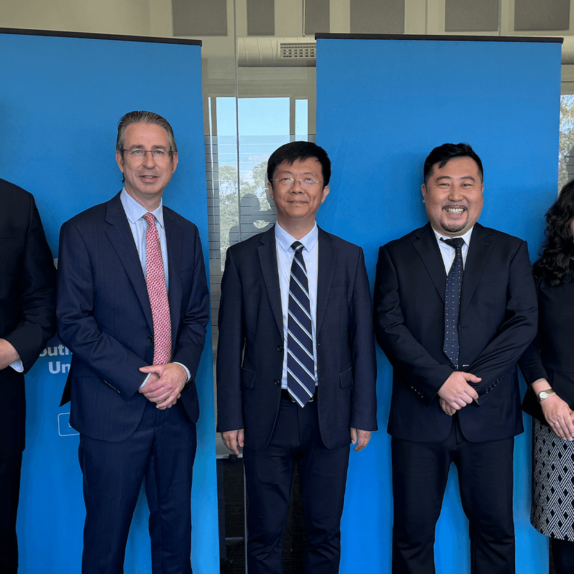Group of people in suits in front of blue pull-up banner