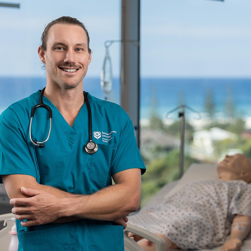 Student in blue polo with stethoscope with sim doll in background