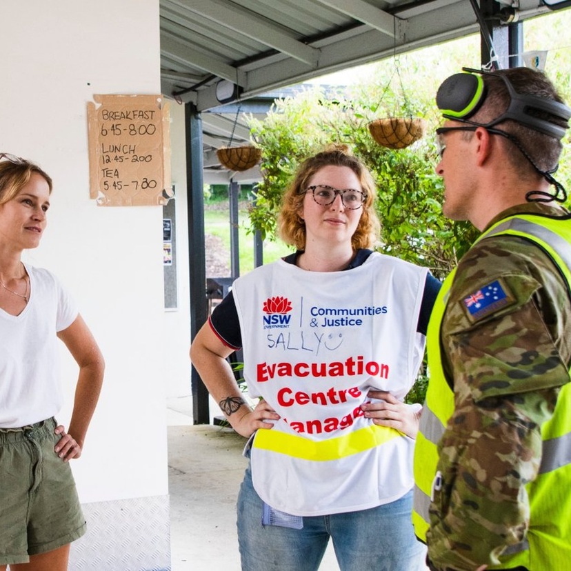 Two women and a man talking in front of a temporary emergency canteen