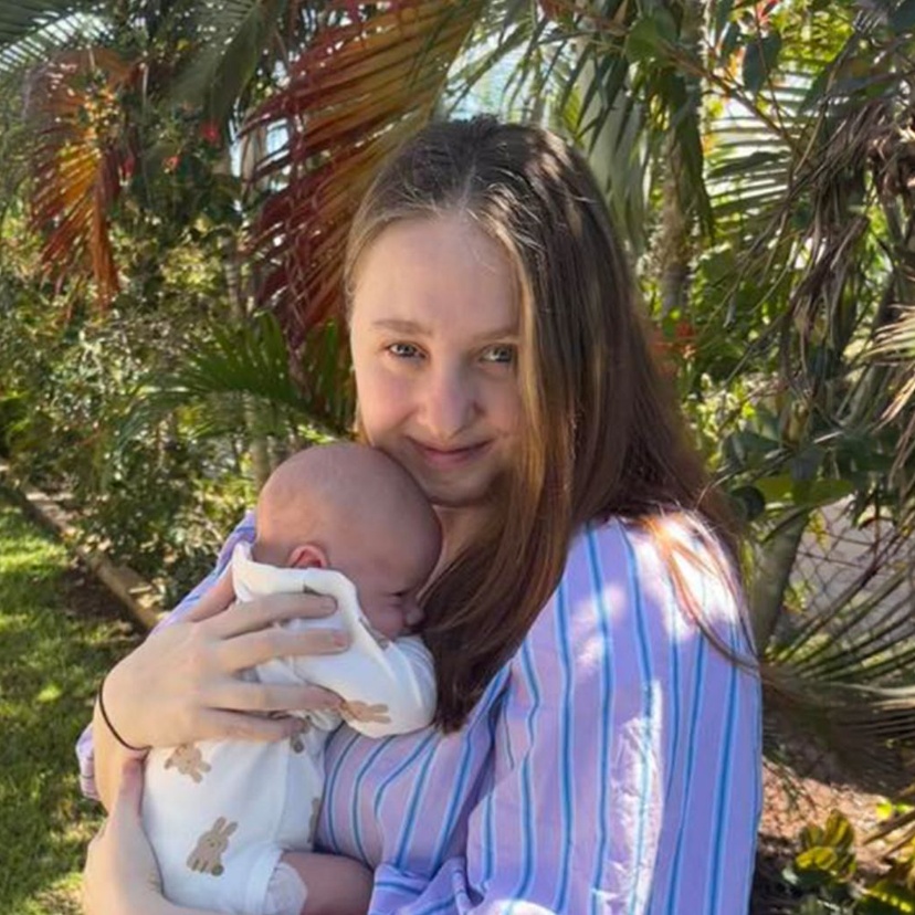 Brittany Elliott faces camera cuddling her baby