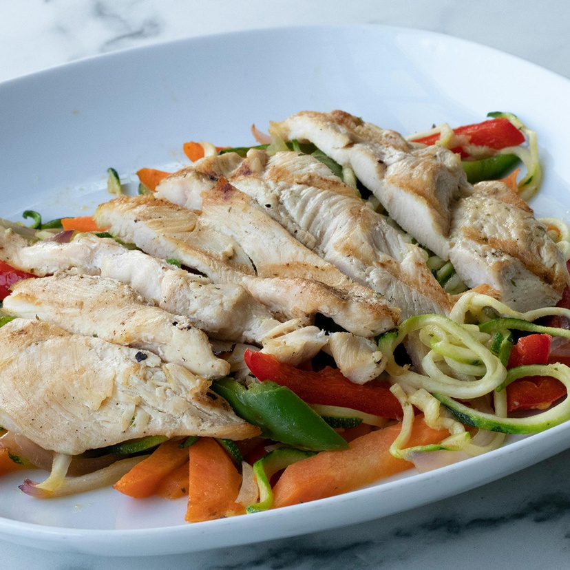 Sliced chicken breast on plate of mixed vegetables