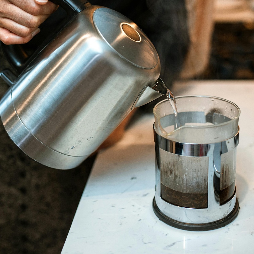 Boiling water poured from kettle into coffee plunger