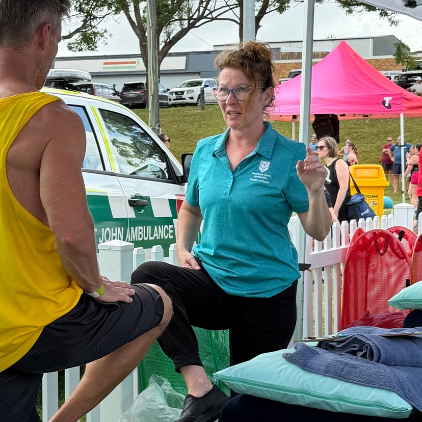 Health student working with athlete, both lifting one leg