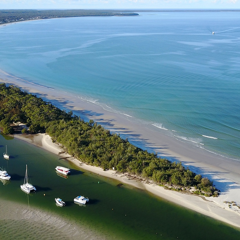 An estuary with boats in the river alongside a beach