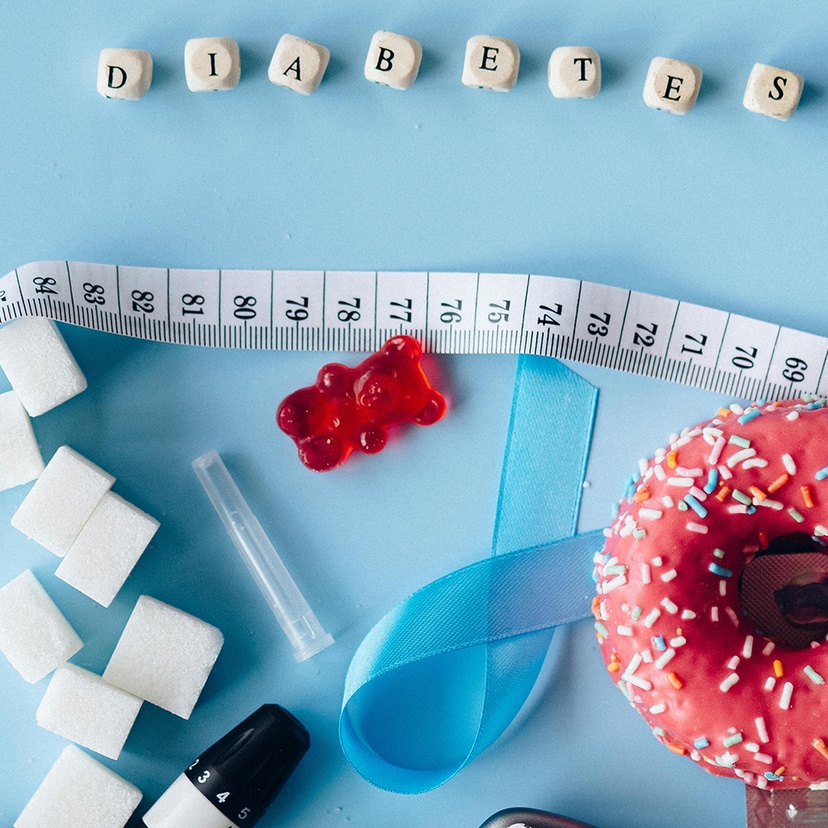 Tiles spelling word diabetes with tape measure, doughnut and sugar