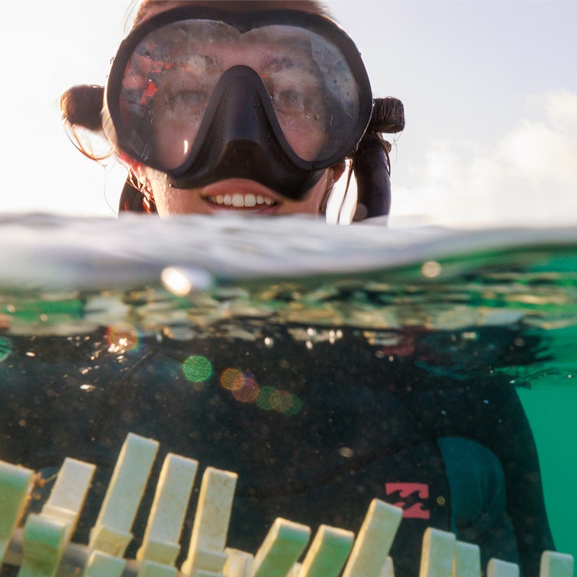 A woman in scuba diving gear holding a skewer of tiles