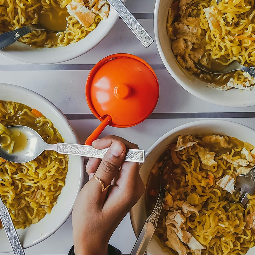 Close-up of a person getting noodles from four different bowls