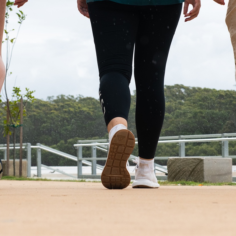 Close-up showing the legs and sneakers of three people walking