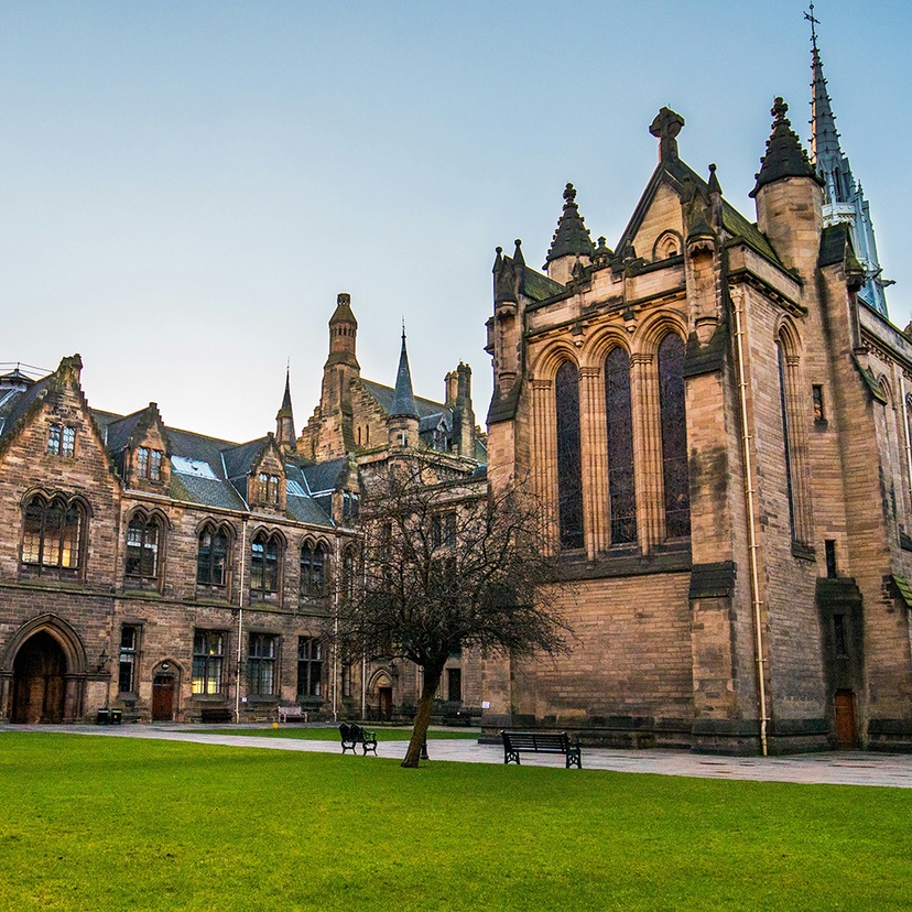 Exterior of a sandstone university with a grass lawn