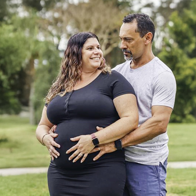 A pregnant woman being hugged by a man