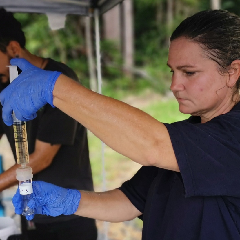 A woman wearing gloves and using scientific instruments in the field