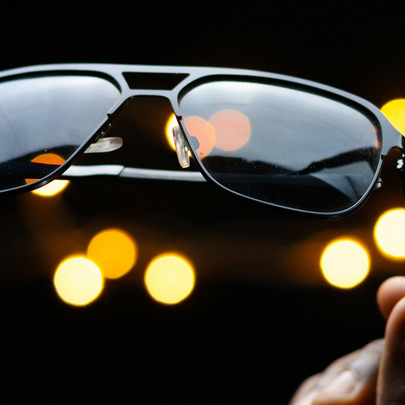 A black set of sunglasses held in a person's hand