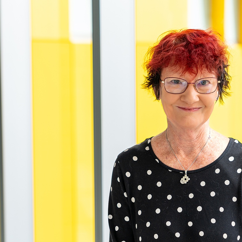 A woman looking at the camera against a modern yellow and glass background