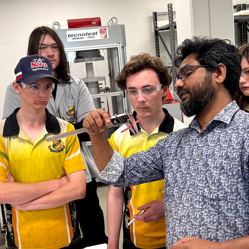 A group of school students and researcher in engineering lab