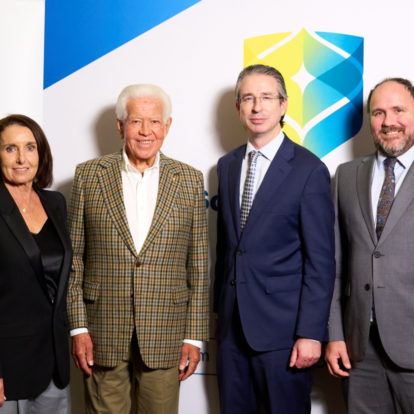 Four people looking at the camera with two colourful banners in the background