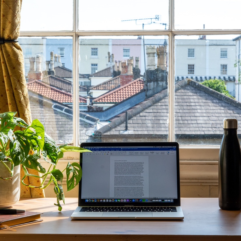 Laptop on desk next to window with views of neighbourhood