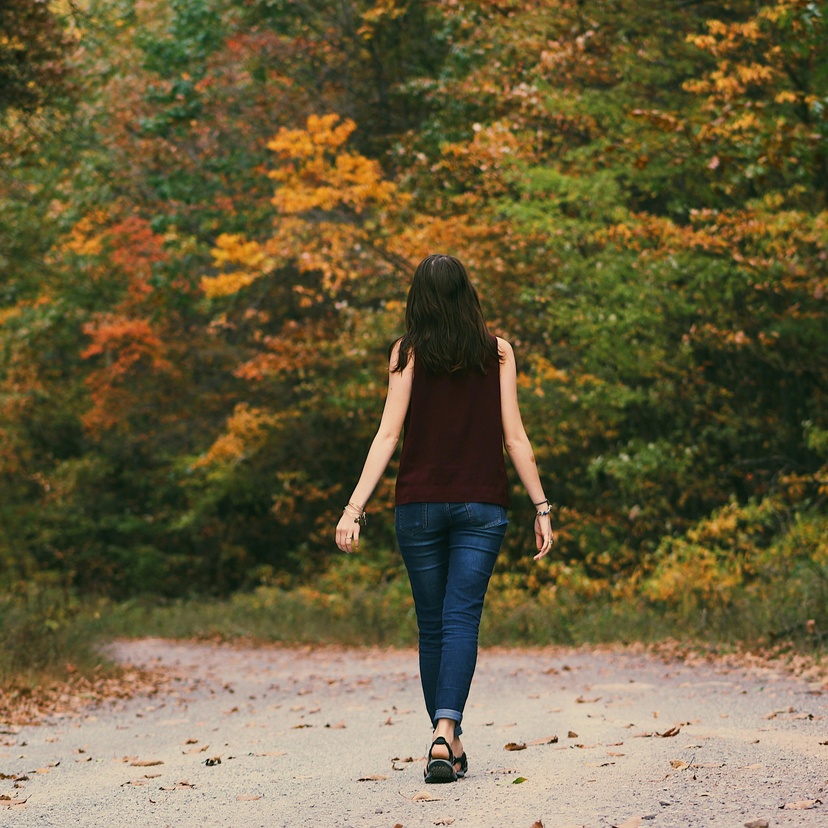 Woman walking away from camera on forest trail