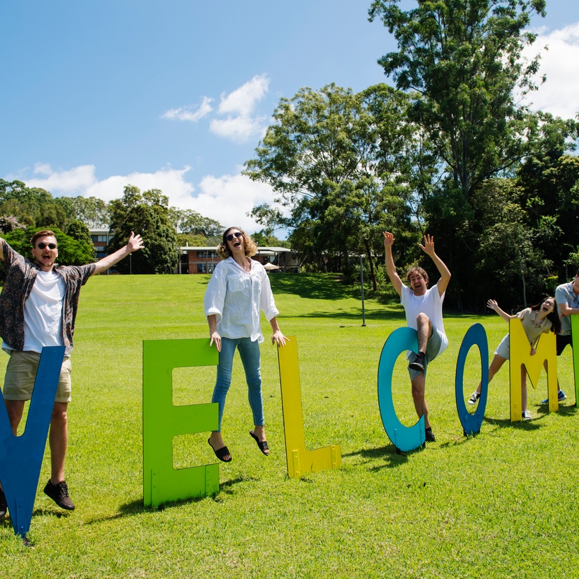 Five students and a welcome sign at Lismore campus