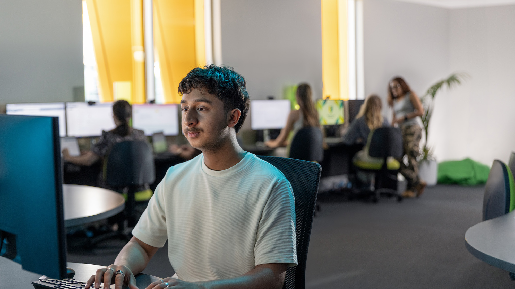 Male student in white shirt using desktop computer