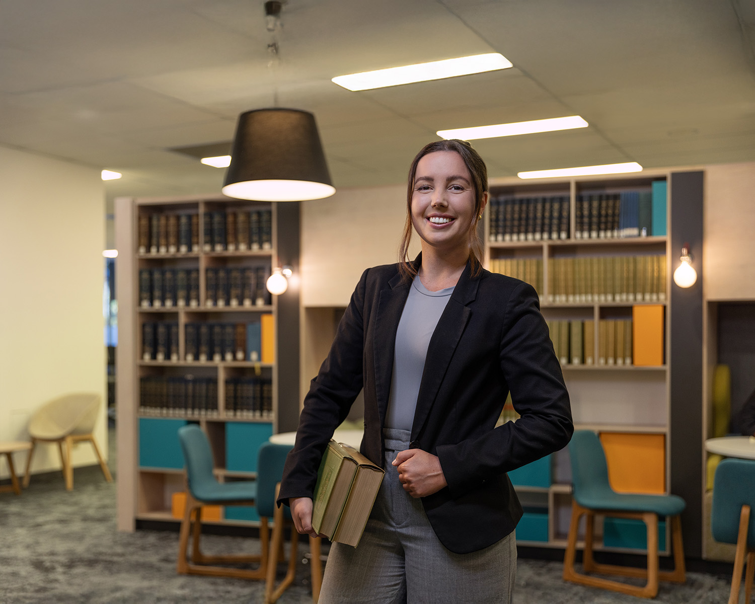 Student in blazer in library with textbooks