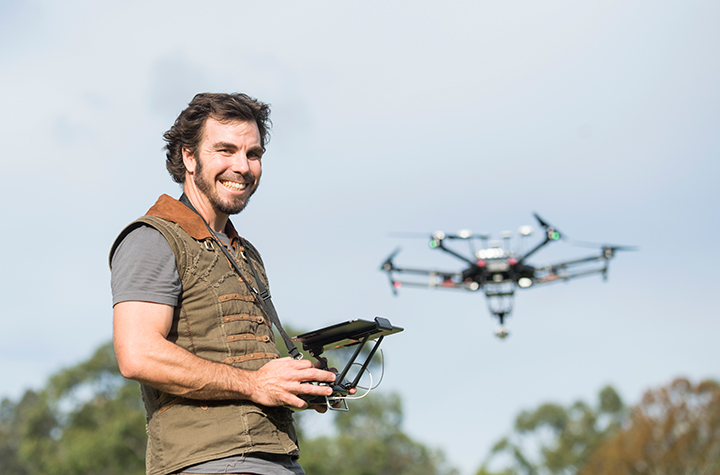 man standing with drone in flight