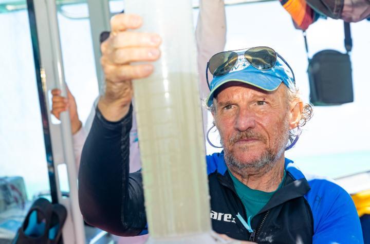 A man inspects a large water container he is holding.