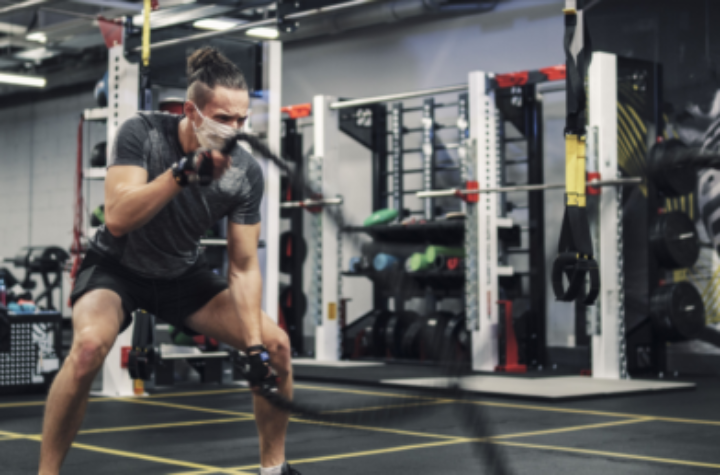 Events and News Man wearing a mask while exercising with battle ropes in the gym