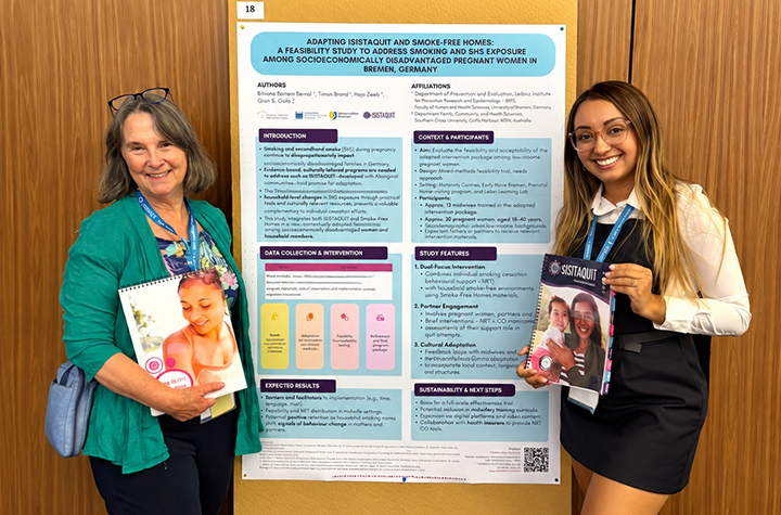 Two women standing alongside a poster