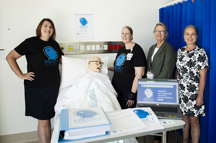 A group of women around a SIM person in a hospital bed